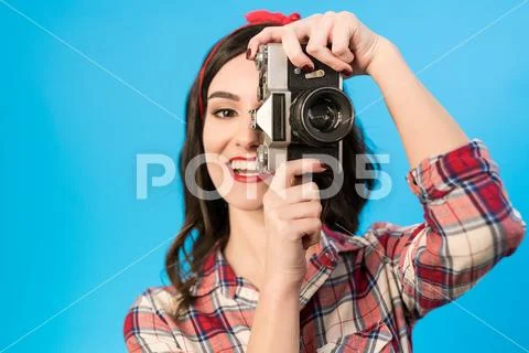 The girl takes a photo with an retro camera on the blue background Stock Photos