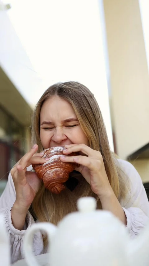 Girl is taking an appetizing bite of  croissant. Breakfast in Paris. Stock Footage 283556547