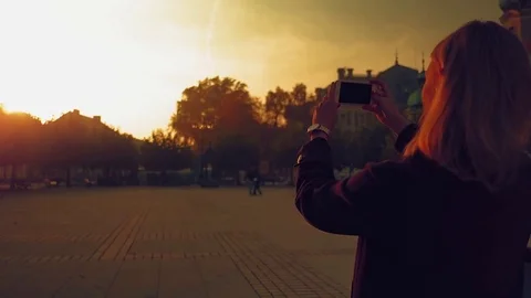 Girl taking photo using smartphone in the city during sunset Stock Footage 82168024