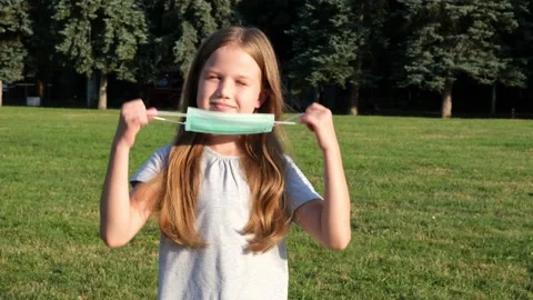 Girl taking off protective face mask in a park and breathing pure fresh air Video stock 158968151
