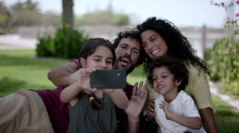 Girl taking selfie with family using mobile camera at park. Stock Footage