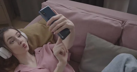 Girl taking a selfie while lying on the couch top view Stock Footage 154337324