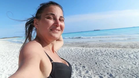 A girl taking selfies while showing the sea and making hand signs Stock Footage 250186901