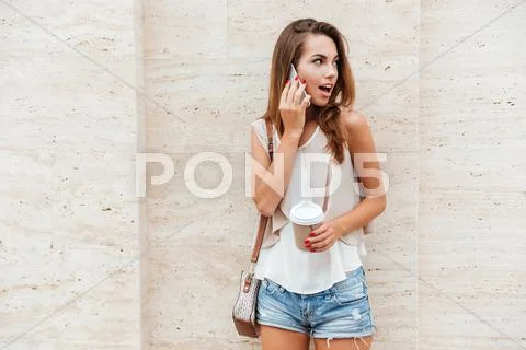 Girl talking on the mobile phone and drinking coffee Stock Photos