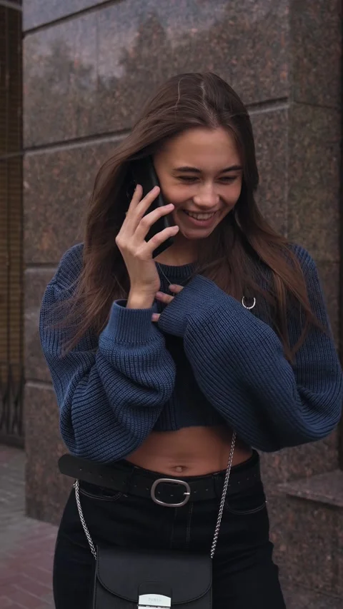 Girl talking by phone and smiling. Looking at camera, vertical video Stock Footage 196702653