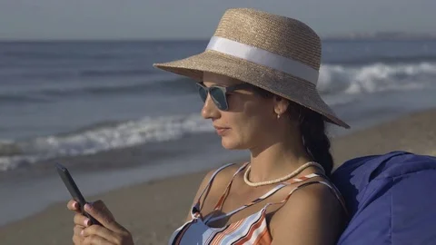 The girl is talking on the phone while sitting on the beach. Stock Footage 79501029