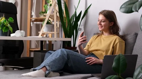 Girl talking on the phone while sitting on the sofa surrounded by indoor Stock Footage 274499865