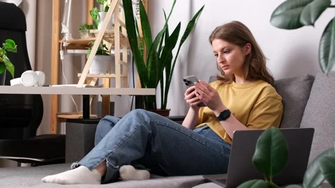 Girl talking on the phone while sitting on the sofa surrounded Stockbeeldmateriaal 274500028
