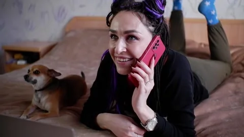 The girl is talking using a mobile phone and smiling while lying on the bed. Stock Footage 170803685