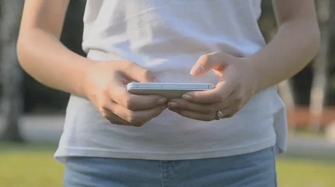 Girl texting using app on smart phone in a park. Stock Footage 57496235