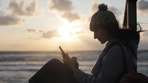 Girl texts and scrolls using phone social media applications at sunset sea sky  Vidéo 92054143