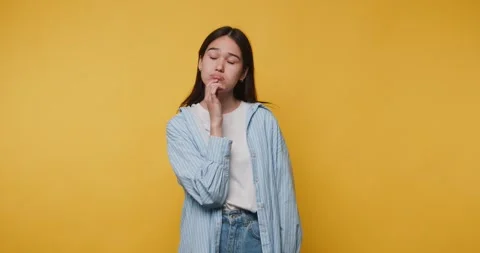 Girl thinks about ideas while standing in front of a yellow wall at a brigh.. Vídeos de archivo 328248241