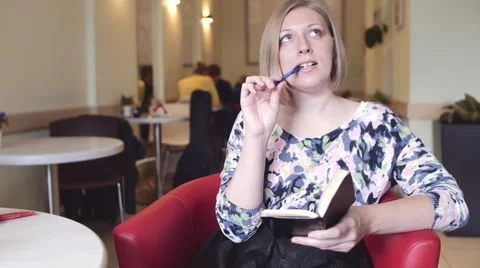 Girl thinks and writes in a notebook in cafe slowmo Video stock 58389035