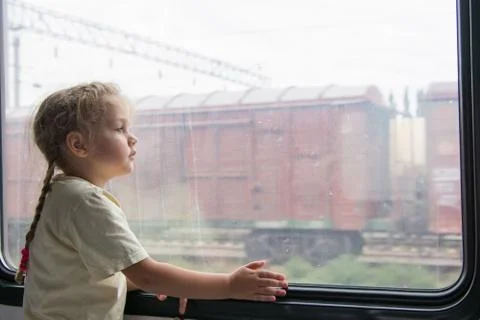 Girl thoughtfully looking into the distance from a train window Stock Photos