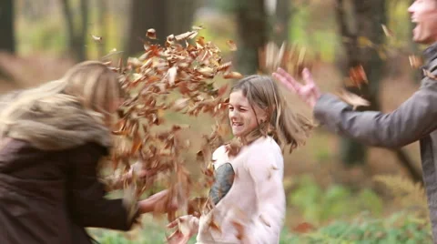 Girl throwing leaves on her parents Stock Footage 59554379