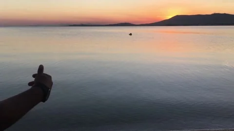 Girl throwing a stone in the pond while watching the sunset 動画素材 134982050