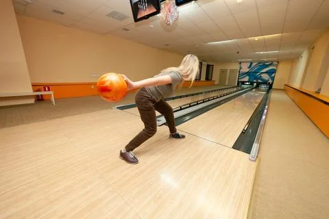 A girl throws a ball while playing bowling. Stock Photos