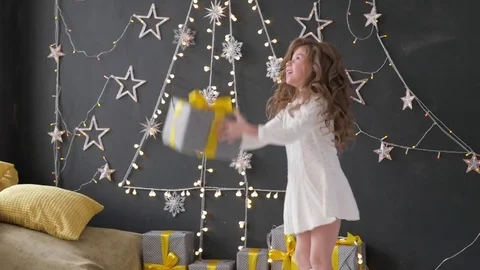 Girl throws a Christmas present on a background of Christmas decorations Stock-Footage 85130645