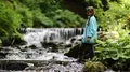 Girl throws stones in a small river HD Footage