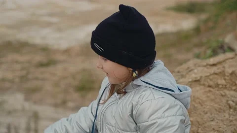 A girl throws stones while sitting on the ground at the edge of a cliff Stock Footage 140417011