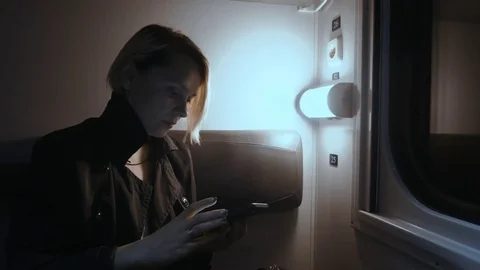 The girl is on the train at night. Sits on the train and uses a smartphone Stock Footage 76536723