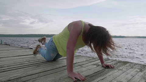Girl tried to do push-ups on wooden pier Stock Footage 79343030
