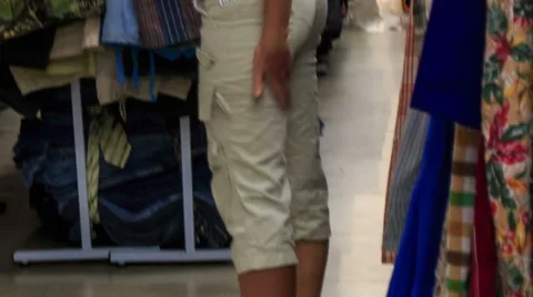 Girl Tries on T-shirt at Racks with Clothes in Shop Stock Footage