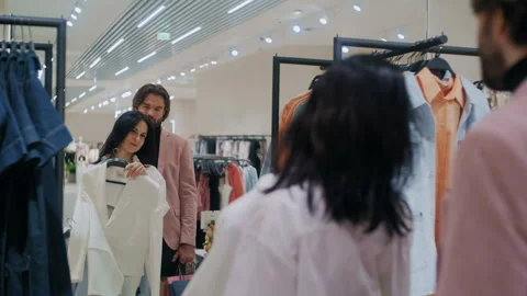 Girl Tries On Two Jackets While Shopping with Boyfriend Stock Footage 311896176