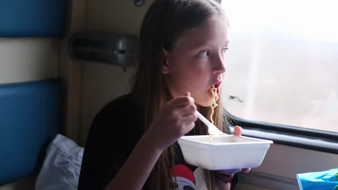A girl on a trip eats noodles while sitting by the window. Stock Footage 272743554