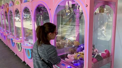 The girl is trying to pull out a soft toy in the slot machine Stock Footage 239326436