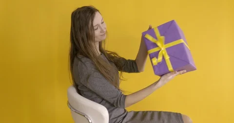 Girl twists in a computer chair while holding a gift package Stock Footage 129157864
