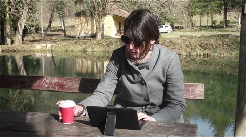 Girl typing on lap top computer and drinking coffee in park. Leisure time.Tablet 스톡 동영상 47405910