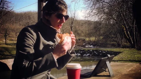 Girl typing on lap top computer or tablet, eating fast food and drinking soda. Video stock 47418118