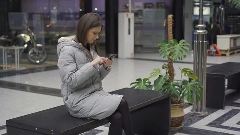 Girl typing on smartphone while sitting on bench and talking to boyfriend Stock Footage 124524475
