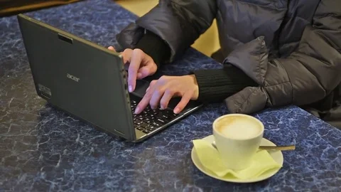 The girl is typing text on a laptop computer. A cup of coffee 4 Stock Footage 83462787