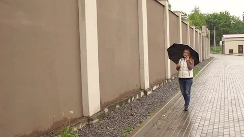Girl with umbrella walking down the street. 4K Stock Footage