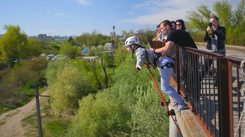 The girl uncertainly with the help of instructors jumping from the bridge Stock Footage 68351059