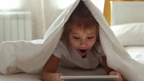 The girl under the blanket looks at the tablet. Stock Footage 169627341