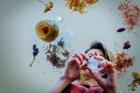 Girl from under glass table while she prepares leaves before brew a tea Stock Photos