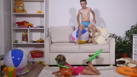 A girl in a underwater mask and flippers swimming in the room, boy playing with Stock Footage