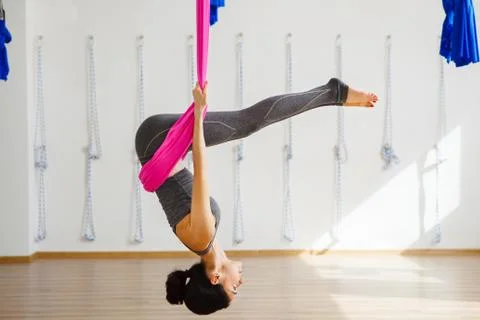Girl in upside down inversion pose on pink silk hammock Stock Photos