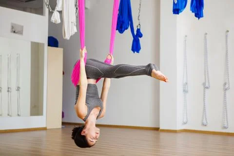 Girl in upside down inversion pose on pink silk hammock Stock Photos
