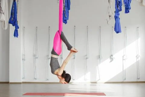 Girl in upside down inversion pose on pink silk hammock Stock Photos