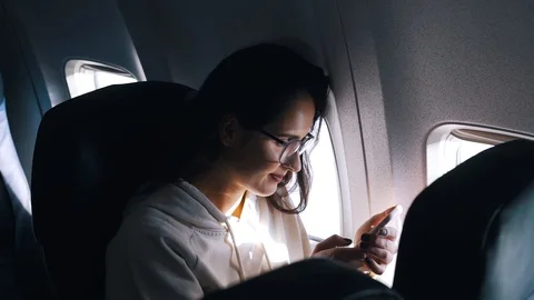 Girl uses a smartphone inside the plane Stock Footage 111149614