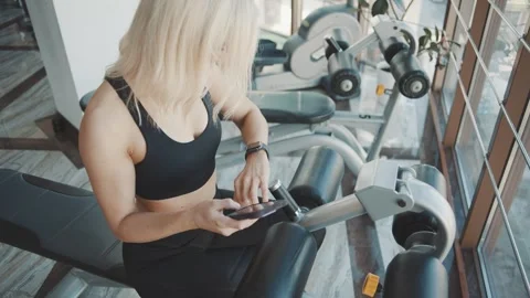 Girl uses smartphone while resting between exercises at the gym Stock Footage 302116447