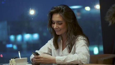Girl uses a smartphone while sitting in a cafe alone. portrait of a teenager in Stock Footage 101790505