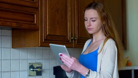Girl uses a tablet computer in the kitchen. Technology and internet concept. Stock Footage 73659847