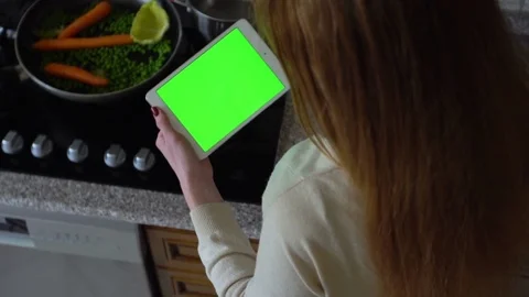 Girl uses a tablet computer in the kitchen. Top view. Green screen. Stock Footage 73659992