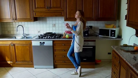 Girl uses a tablet computer in the kitchen. Technology and internet concept. Stock Footage 73688956