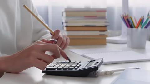 Girl using calculator while studying at table in house Stock Footage 292728163